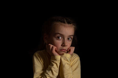 A child on a dark background thinks and dreamsの写真素材