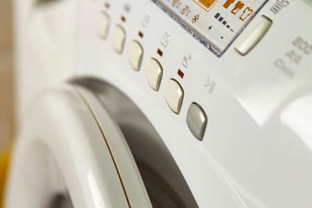 Modern washing machine with laundry. Close-up of control buttons and panel