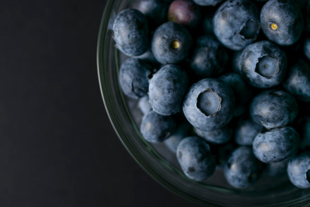 Bowl of blueberries on black background. Macro photography of fresh blueberries. Ripe blueberries background. Blueberries texture. Food photography collection.の写真素材