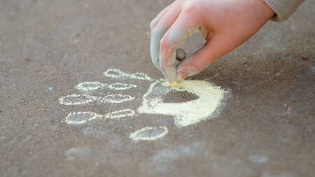 Girl drawing with colored chalk on the pavementの写真素材