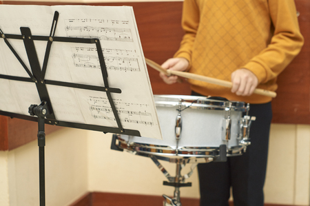 Boy playing drum looking to notes during the school fairの写真素材
