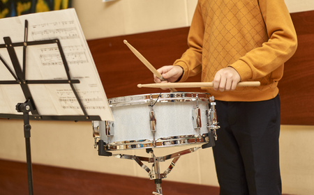 Boy playing drum looking to notes during the school fairの写真素材