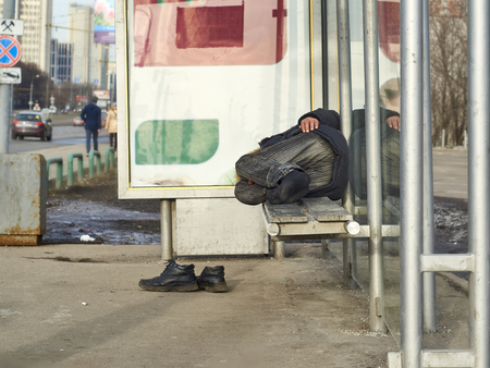 Real beggar sleeping on bus stop