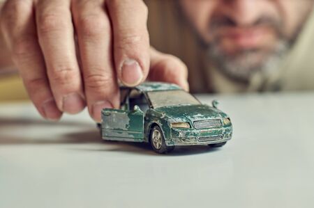 Middle-aged bearded man plays with shabby old toy carの写真素材