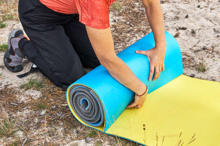 Hiker woman rolling camping mats on the gound in the forestの写真素材