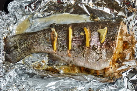 Trout with slices of lemon prepared in an aluminum foilの写真素材