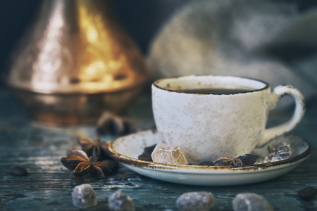 Still life with cup of coffee and turkish coffee pot with coffee beans lying on a shabby wooden tableの写真素材