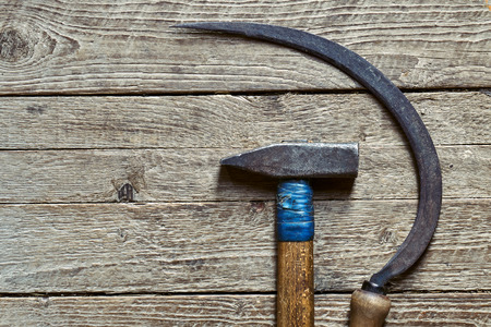 Old rusty sickle and hammer lying on wooden background with a copy spaceの写真素材