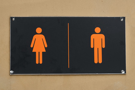 Black signboard with silhouettes of man and woman on the lavatory door