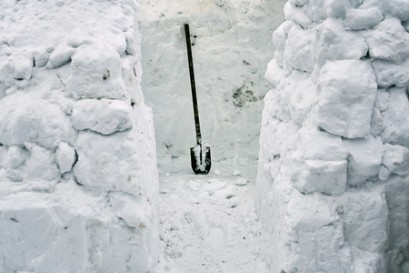 Building of a snow house in a cold winter from snow bricks using a spade
