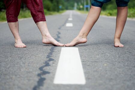 Barefoot legs of an adult woman and a young girl on the asphalt road. Low angle view.の写真素材