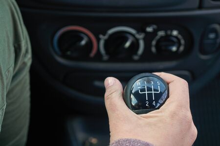 Young girl is switching gears in the car with a manual gearbox using gearshift