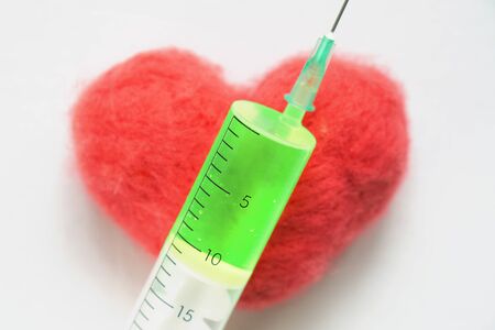 Syringe with a green medicine lying on a red heartの写真素材