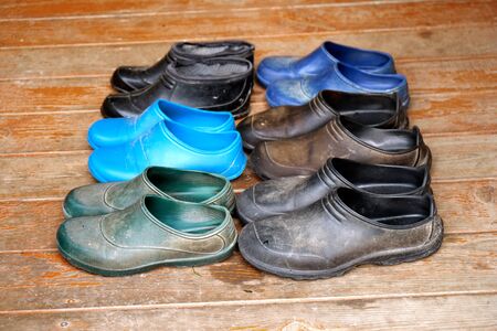 Old rubber boots of a big family stand on the wooden floorの写真素材