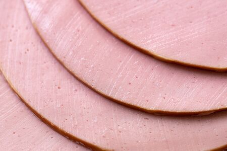 Slices of a tasty fresh boiled sausage macro. Sliced boiled delicious sausage close-up