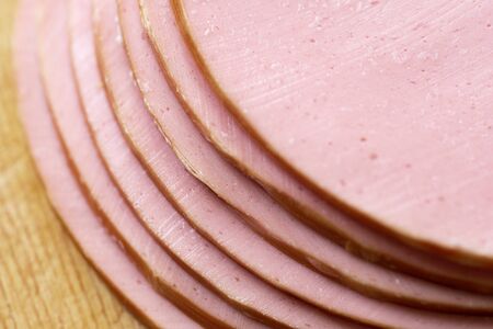 Slices of a tasty boiled sausage on the wooden board