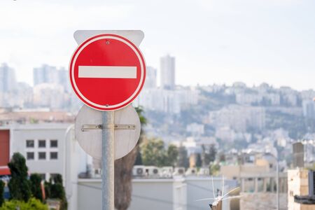 Red do not enter road sign with an Israeli town Haifa on the backgroundの写真素材
