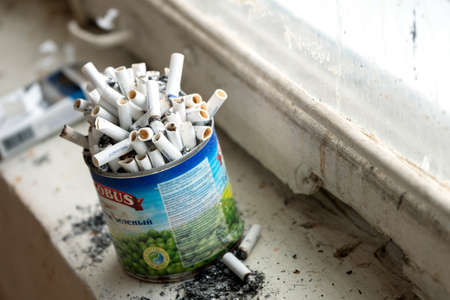Moscow,Russia-March 15, 2020. Tin can used as an ashtray full of the smoked cigarettes standing on the windowsill. Above viewのeditorial素材