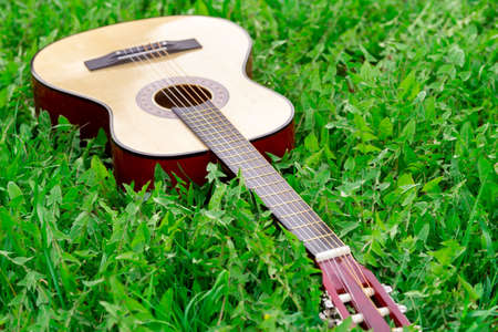 Wooden acoustic guitar lying on the green grass outdoors in summerの写真素材