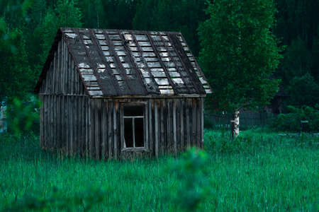 Old small poor village house in high grass at nightの写真素材