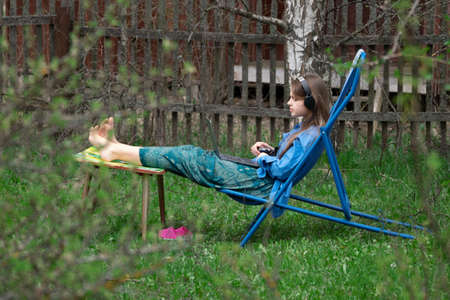 Teen girl takes part in a school online webinar sitting outdoors in springtime