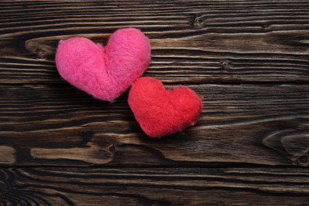 Two woolen handmade hearts on the dark brown wooden boardsの写真素材