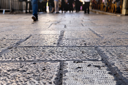 Ancient pavement stones on the old Jerusalem street close up with feet of walking people on the backgroundの写真素材