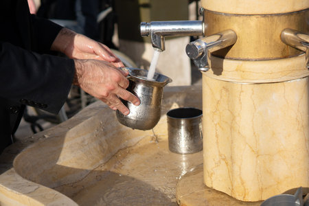 Hands of a Jewish orthodox man washing hands using a traditional ritual cupの写真素材