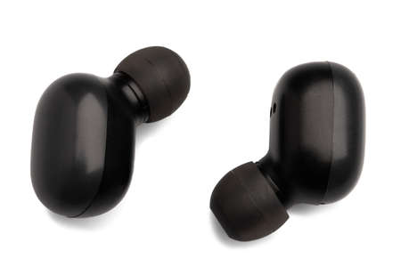 Black wireless earphones isolated on a white background with shadows. Modern wireless headphones.