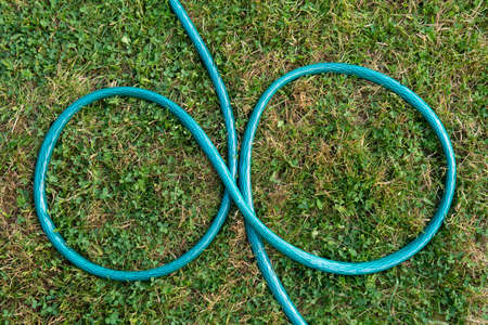 Garden hose lying on the green grass in the form of an infinity signの写真素材