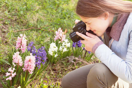 Teenage girl taking photos of hyacinth flowers by a digital camera in the spring gardenの写真素材