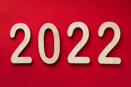 2022 year wooden numbers lying on the red paper background with shadows