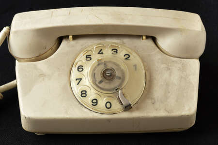 Dirty Retro dial phone covered with a layer of dust on black cloth