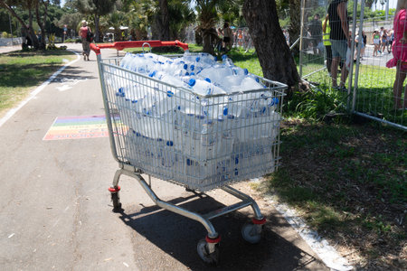 Tel Aviv Yafo, Israel - June 10, 2022. Shopping cart full of bottles of water stands outdoors in hot sunny weatherのeditorial素材