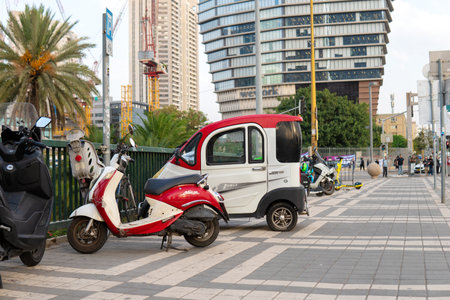 Tel Aviv Yafo, Israel - October 26,2022.Scooter and a small car parking on a sidewalk in Tel-Avivのeditorial素材