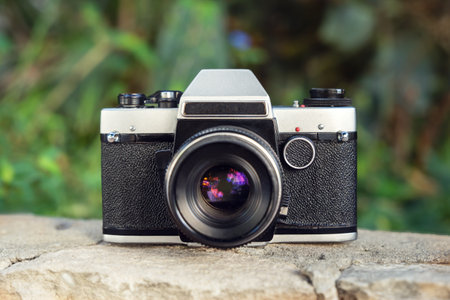 Old photo camera on a cement wall with tropical vegetation on the background outdoorsの写真素材