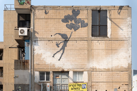 TEL AVIV, ISRAEL-February 27, 2024: Graffiti depicting a magical boy flying on heart-shaped balloons on a wall of a house in Tel Avivのeditorial素材