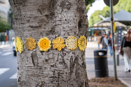 Tel Aviv, Israel - March 15, 2024. Knitted woolen flowers on a tree trunk on the Rothschild boulevard in Tel Avivのeditorial素材