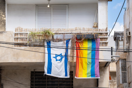 LGBT flag and an Israeli flag hang from the balcony of an apartment building