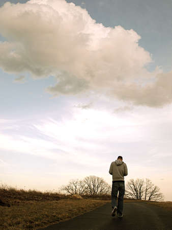 man walking under cloudsの写真素材