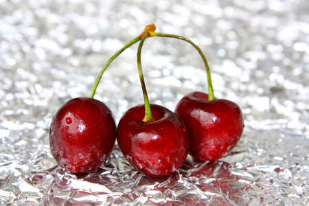 Three ripe berries of a sweet cherry on a foilの写真素材