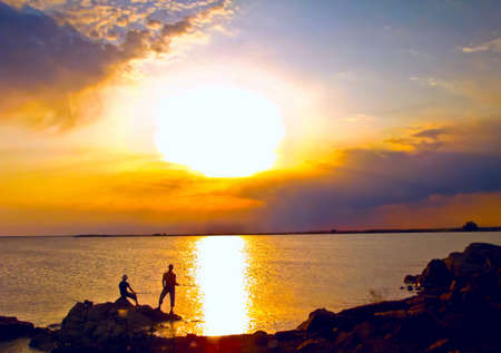 Beautiful sunset, coastline, two fisher man  at the sea                         の写真素材