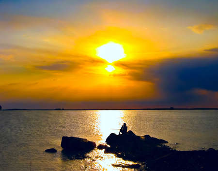 Silhouette, sunset, fisher man at the sea.の写真素材