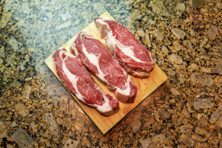 3 raw ribeye on a wooden board white backgroundの写真素材