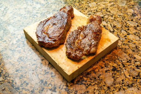 2 prime ribeyes cooked in medium rare on a wooden board white backgroundの写真素材