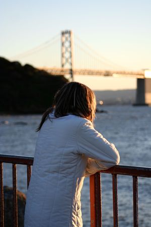 Girl on the beach looking at Bay Bridge in San Francisco, ca.