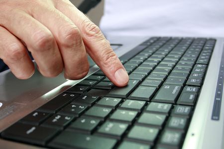 Fingers on keypad of silver and black laptop