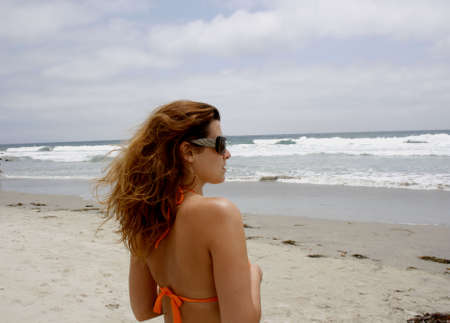 Girl at the beach looking to oceanの写真素材