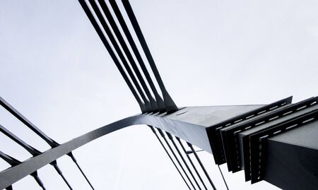 Details of urban architecture, gray lines of the bridge against the light blue sky background.の写真素材