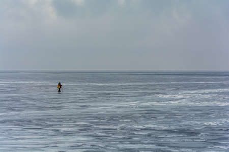 A lonely man walks through a frozen lake